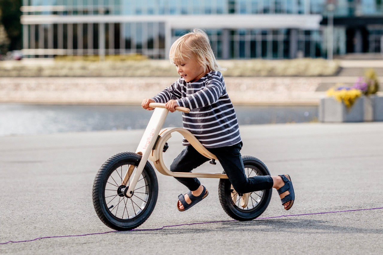 Child riding wooden balance bike in summer outdoor scene — Balance Bike 3in1 — AlmaVidaKids