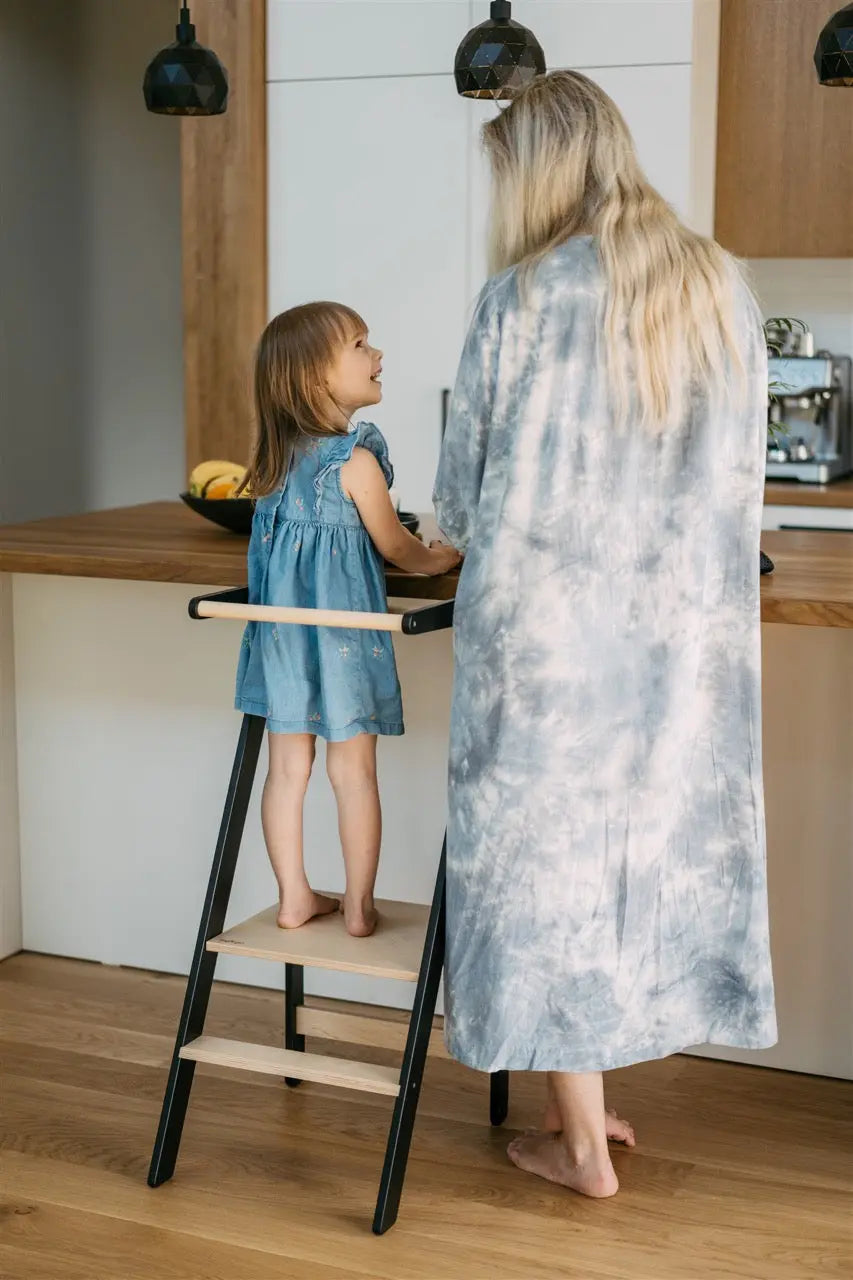 Woman and child in a kitchen with the child on a learning tower.