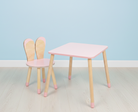 Family-scl Bunny tafel en één stoel met konijnenoren in roze en naturel hout, voor een lichtblauwe muur.
