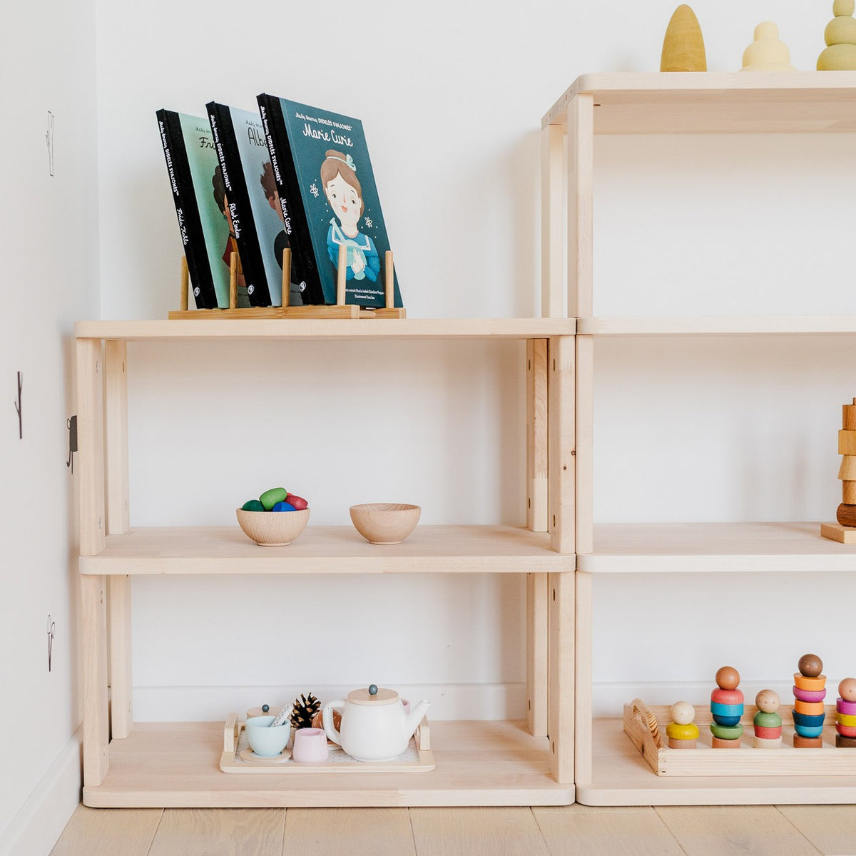 Close-up of Straight Mini wooden shelving styled with books and toys beside another shelving unit.