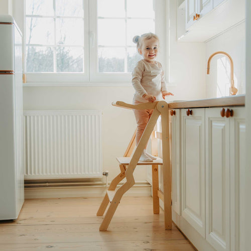 Child using the natural ZigZag foldable learning tower at a kitchen counter
